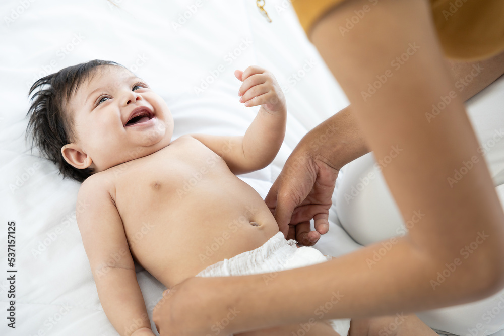 mother changing diaper a newborn baby lying on the bed