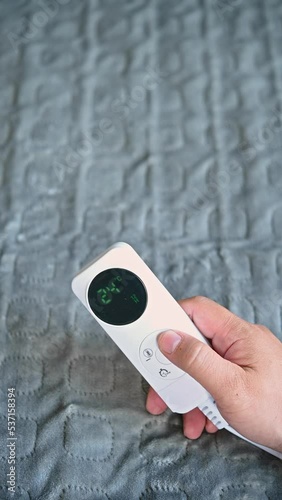 man operating a controller of an electric blanket vertical composition