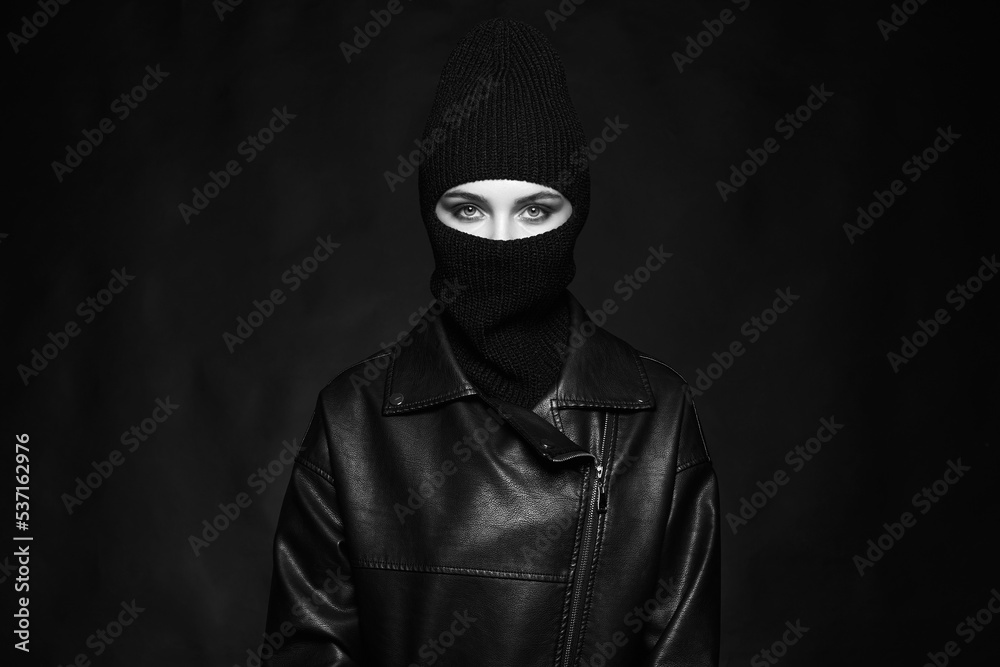 Fashionable girl in balaclava and leather coat. Black and white portrait