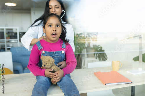 sick Indian girl in consultation with her female doctor - health concept -