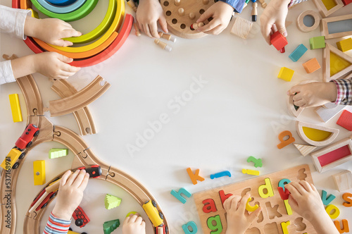 Children play wooden eco-friendly and colored toys. Dice, blocks, alphabet, railroad and board games. Montessori material.