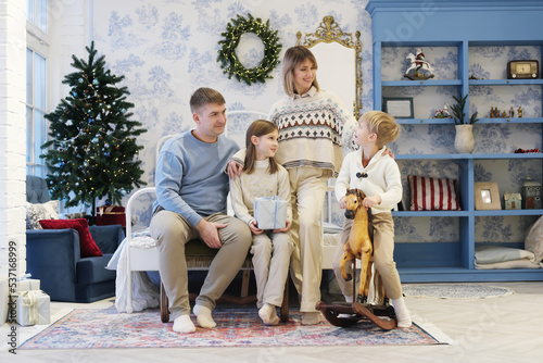 A family of four pose in a Christmas interior. Family communicates with each other