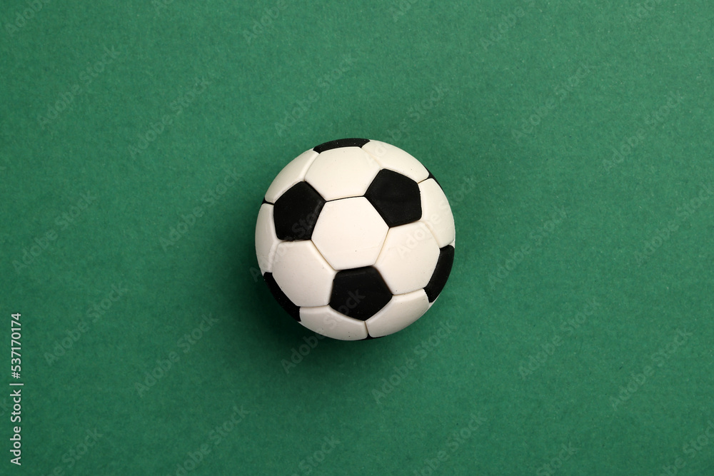 miniature toy football soccer ball black and white colour over green background copy text space concept