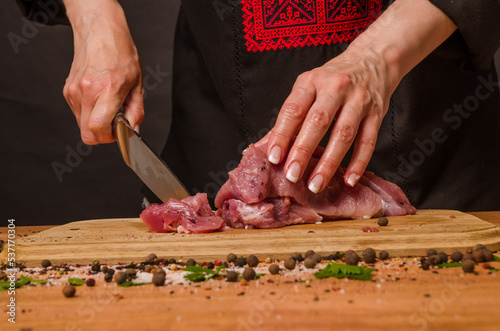 Female hands with a knife in their hand cut fresh meat on a table photo