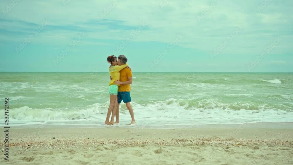 Romantic couple running on beach at sea holding hands and kissing. Man tenderly hugging woman. Concept of love and happiness outdoors Romantic couple running on beach at sea holding hands and kissing. Man tenderly hugging woman. Concept of love and happiness outdoors