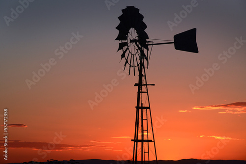 A warm Australian sunset silhouettes the irrigation pump in the paddock against the rich sky