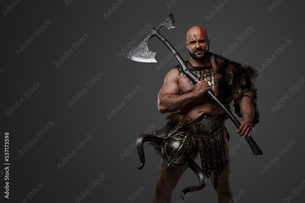 Shot of scandinavian barbarian with fur and horned helmet holding two handed axe. Shot of scandinavian barbarian with fur and horned helmet holding two handed axe.