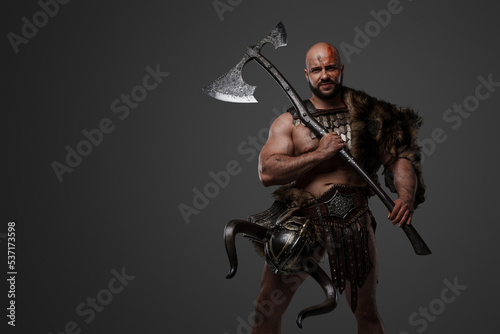 Shot of scandinavian barbarian with fur and horned helmet holding two handed axe.