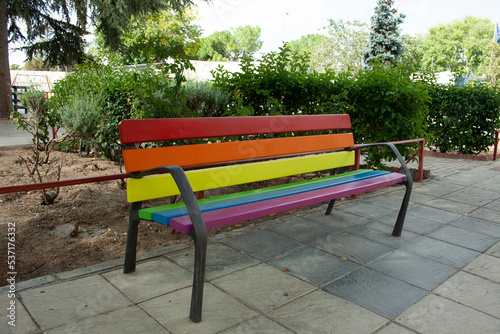 Bench in a park painted in the colors of the lgtb pride flag