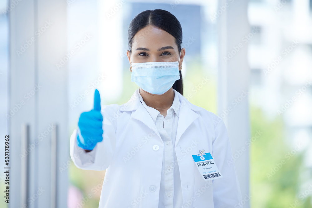 Doctor, mask and thumbs up at work in hospital, clinic or office for success in healthcare. Medic, woman and professional in medical ppe do hand sign to agree in health, medicine and community safety Doctor, mask and thumbs up at work in hospital, clinic or office for success in healthcare. Medic, woman and professional in medical ppe do hand sign to agree in health, medicine and community safety