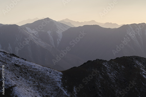 Horizontal landscape with mountain snowy peaks at sunset.