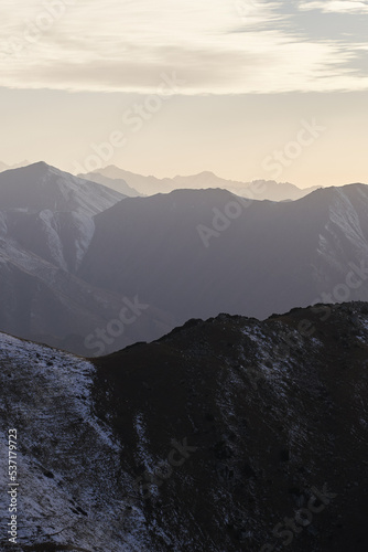 Vertical landscape with a view of mountain peaks with snow at sunset.