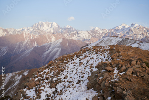 Scenery view on a rocky mountain range covered with snow at sunset.