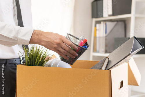 Unemployed, quite job. Desperate caucasian young businessman resigning from company, hand holding stuffs into the cardboard, packing belongings, layoff or changing work. Resignation,employment concept
