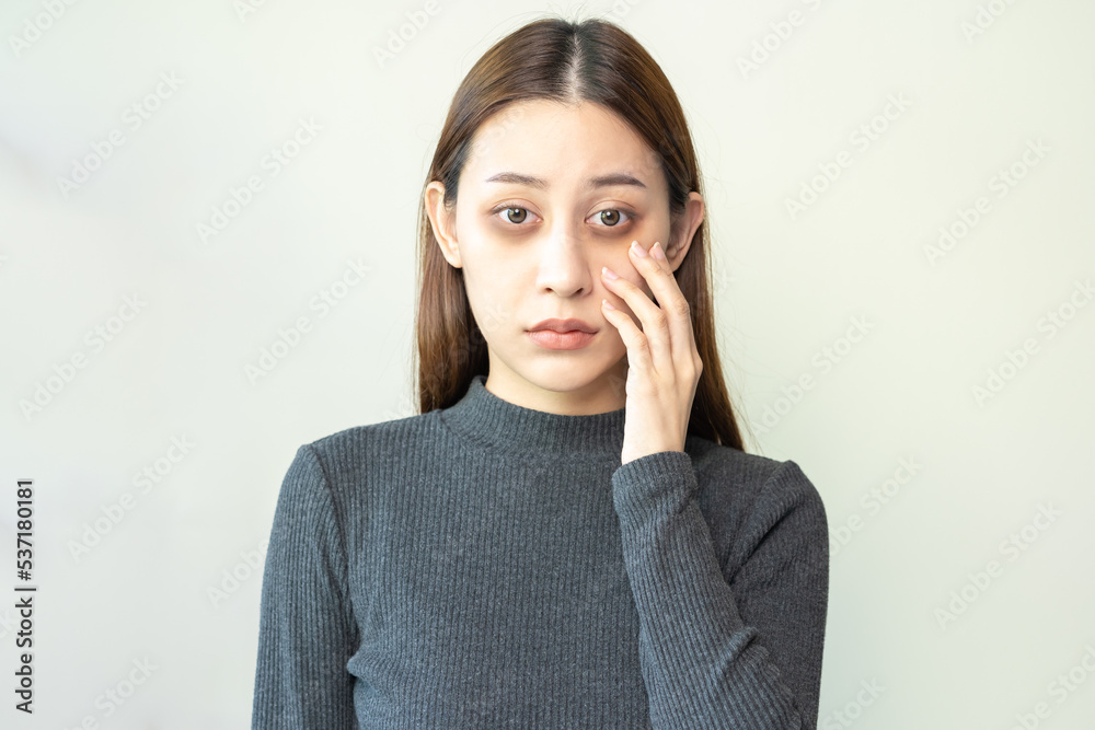 Bored, insomnia asian young woman, girl looking at camera, hand touching under eyes with problem of black circles or panda puffy, swollen and wrinkle on face. Sleepless, sleepy healthcare person. Bored, insomnia asian young woman, girl looking at camera, hand touching under eyes with problem of black circles or panda puffy, swollen and wrinkle on face. Sleepless, sleepy healthcare person.