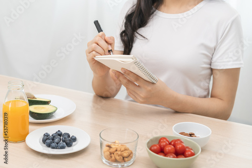 Diet, Dieting hand of asian young woman, girl write diet plan nutrition on table is different food ingredients in the green. Nutritionist of healthy, nutrition of weight loss, health care people.