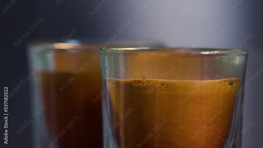 Aromatic double espresso dripping into glasses with foamy crema on top Aromatic double espresso dripping into glasses with foamy crema on top