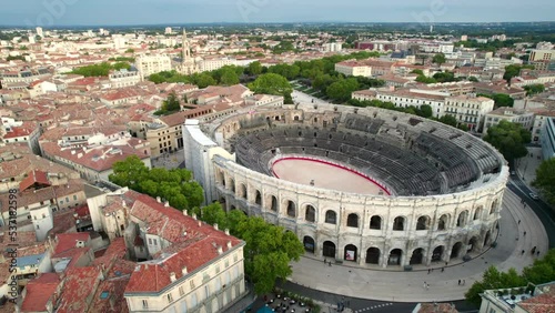 Old Roman arena still in use in the modern city of Nimes, France. Downtown Nimes, panoramic drone shot.