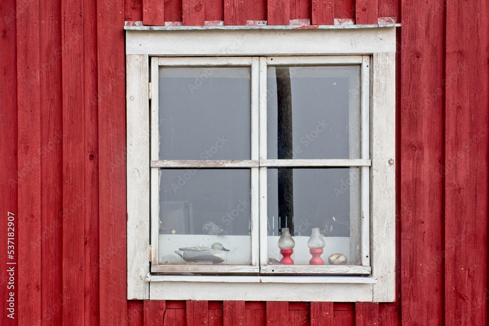 Red wood building with white framed window.