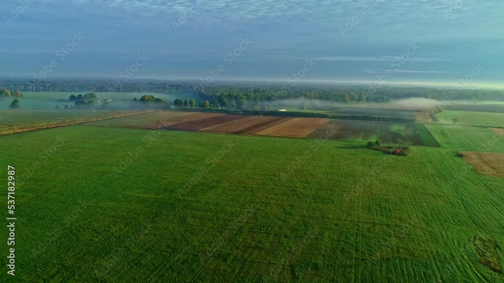 Aerial backwards shot of beautiful agricultural fields during foggy and sunny day - Blue sky in countryside area Aerial backwards shot of beautiful agricultural fields during foggy and sunny day - Blue sky in countryside area