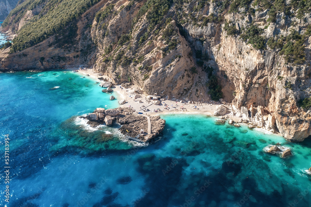 Aerial view beautiful seascape with stone dock and small sandy beach top view. Sea coast with blue, turquoise clear water on a sunny day, aerial drone shot