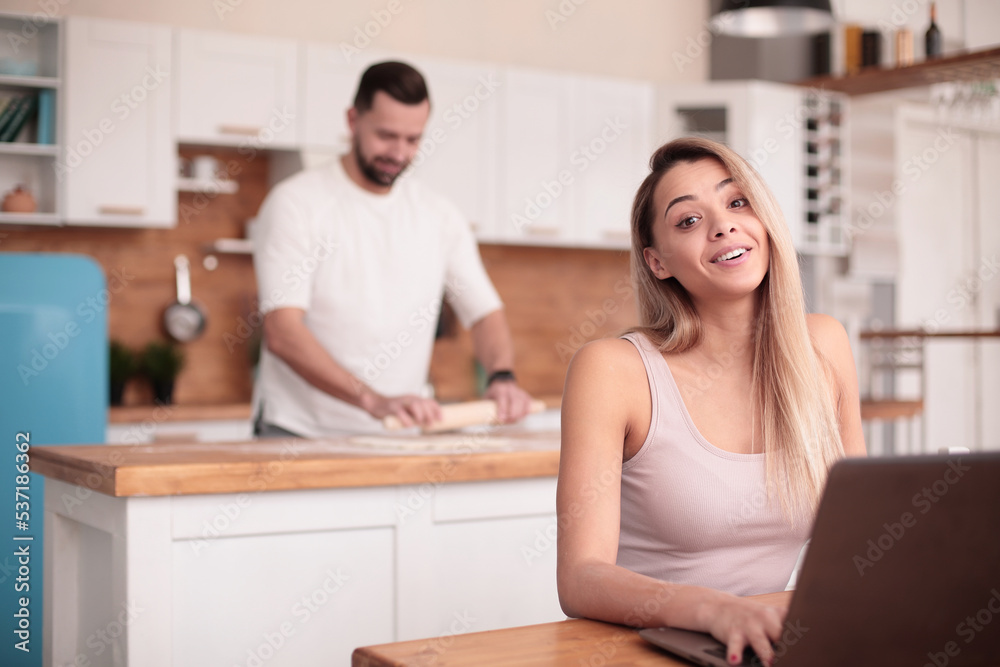 young woman sitting in front of open laptop in kitchen young woman sitting in front of open laptop in kitchen