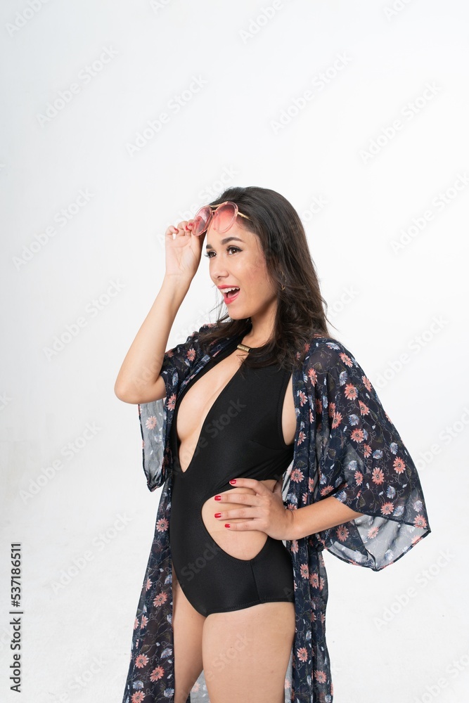 Studio portrait photo of a young beautiful elegant Brazilian female model lady wearing black color swimsuit bikini, sunglasses and beach scarf posing with a series moments of emotion and gesture Studio portrait photo of a young beautiful elegant Brazilian female model lady wearing black color swimsuit bikini, sunglasses and beach scarf posing with a series moments of emotion and gesture