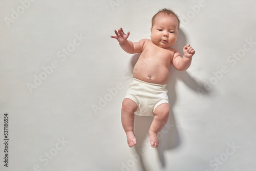 A newborn baby lying full-length on a light-colored surface