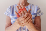 an elderly woman suffering from pain in her hand rubs her wrist, close-up