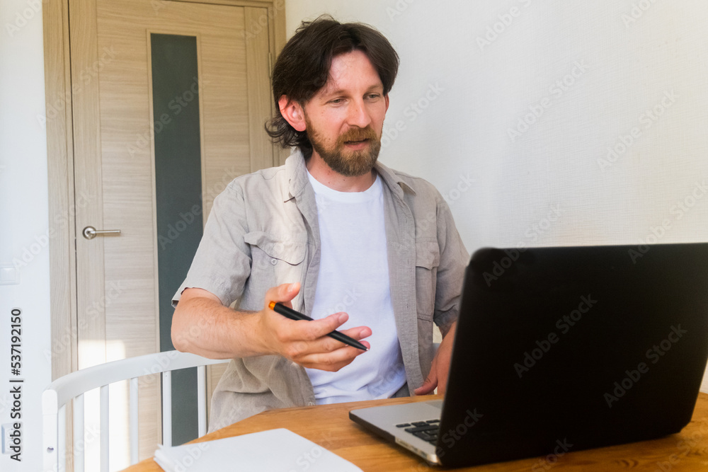 Bearded man says something to the laptop monitor. Remote work concept Bearded man says something to the laptop monitor. Remote work concept