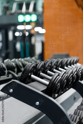 Close up set of dumbbells on black metal steel on rack in sports fitness center.