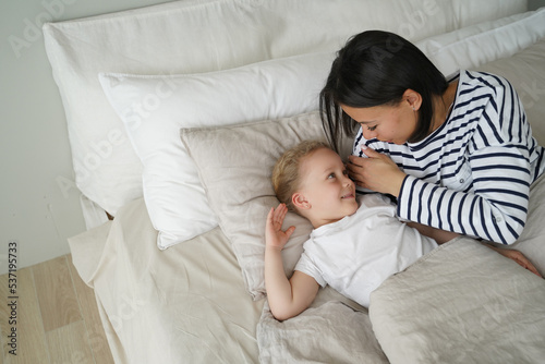 Young mom lying in bed with little kid daughter after sleeping in bedroom. Healthy children's sleep