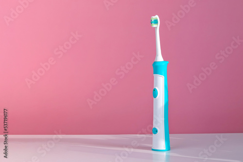 Electronic ultrasonic toothbrush, on a pink background, on a white table. A toothbrush for children. Copy space © Сергей Стельченко