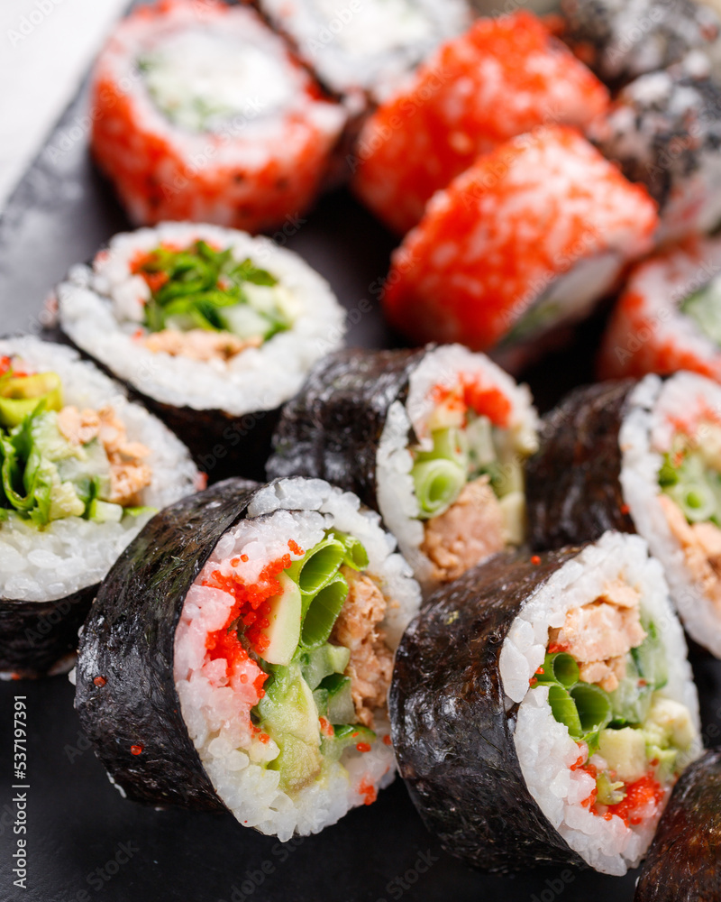 Large sushi set of various sushi rolls is served on black square metal slate. Large sushi set of various sushi rolls is served on black square metal slate.