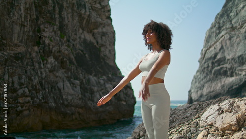 Girl practicing yoga exercises standing rocky Ursa coast. Woman crossing hands.