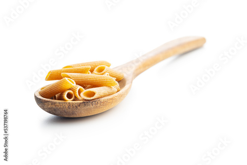 Uncooked whole grain pasta isolated on white background. Raw penne pasta on spoon.