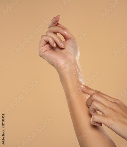 Close up cropped woman apply hand perfect skin hand cream isolated on beige studio background.