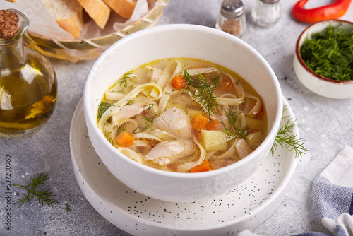 Chicken soup with noodles, potatoes and carrots. Delicious homemade clear broth soup, served with dill and white bread.