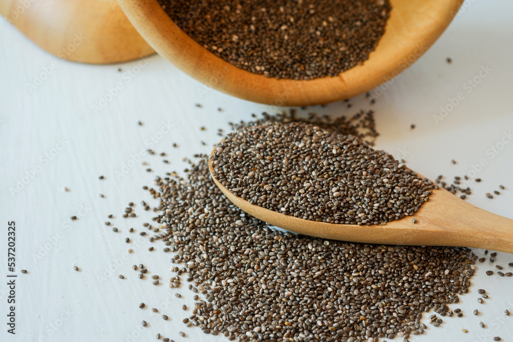 Chia seeds stack and spoon with wooden bowl on white background. Chia seeds stack and spoon with wooden bowl on white background.
