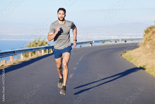 Fototapeta Naklejka Na Ścianę i Meble -  Fitness, man and running on a mountain road in South Africa for healthy cardio workout in the outdoors. Active athletic male runner in sports training having a run on the street in nature