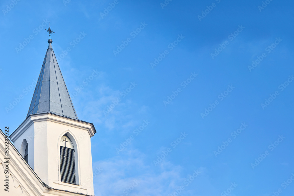 White church steeple with cross with window blind and cross over blue sky background. Religious easter background with copyspace White church steeple with cross with window blind and cross over blue sky background. Religious easter background with copyspace