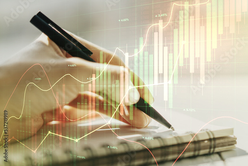 Double exposure of abstract creative financial chart with hand writing in notebook on background, research and strategy concept