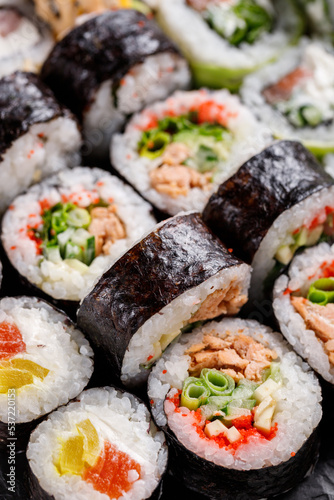 Close up of original sushi rolls with different fillings standing and lying close to each other.