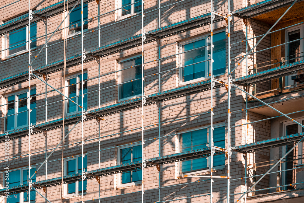 Part of construction site with scaffolding on multistory building facade during renovation