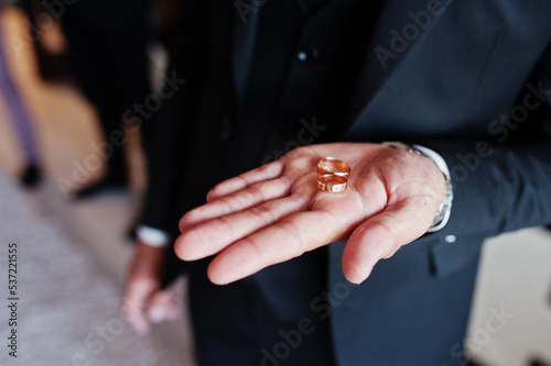 Groom holding wedding rings in hand.