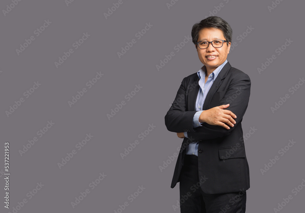 Portrait of a businesswoman with short black hair in a suit while standing with arms crossed on a gray background Portrait of a businesswoman with short black hair in a suit while standing with arms crossed on a gray background