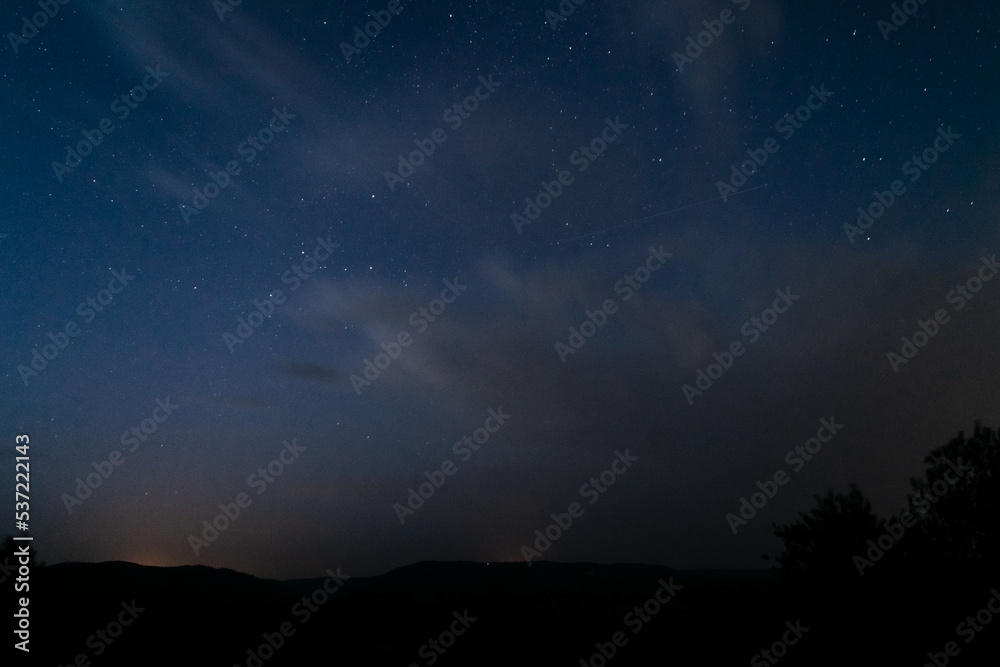 Cielo nocturno con estrellas, nubes y silueta de montañas. Perseidas. Cielo nocturno con estrellas, nubes y silueta de montañas. Perseidas.