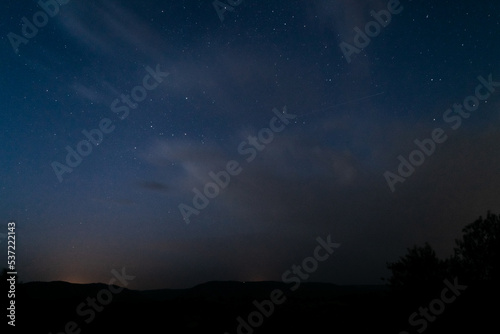 Cielo nocturno con estrellas, nubes y silueta de montañas. Perseidas.  photo