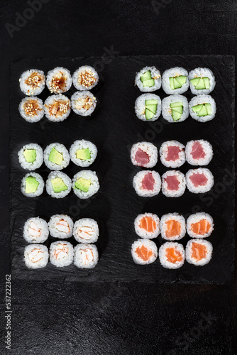 Different types of delicious and juicy sushi and rolls on a wooden board