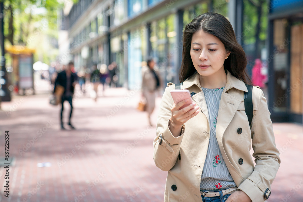 asian chinese woman tourist standing on pedestrian walk and using smartphone for online guide while touring around downtown san Francisco in California usa on as sunny day asian chinese woman tourist standing on pedestrian walk and using smartphone for online guide while touring around downtown san Francisco in California usa on as sunny day